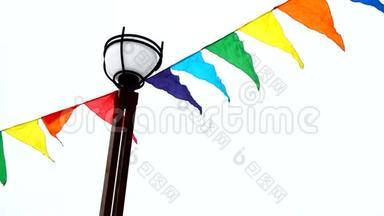 五颜六色的三角旗在风中飘扬，系在灯柱上。 假日装修，室外装修